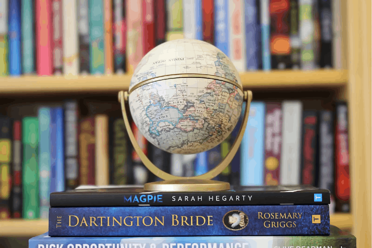 A globe resting on books in front of a packed bookshelf