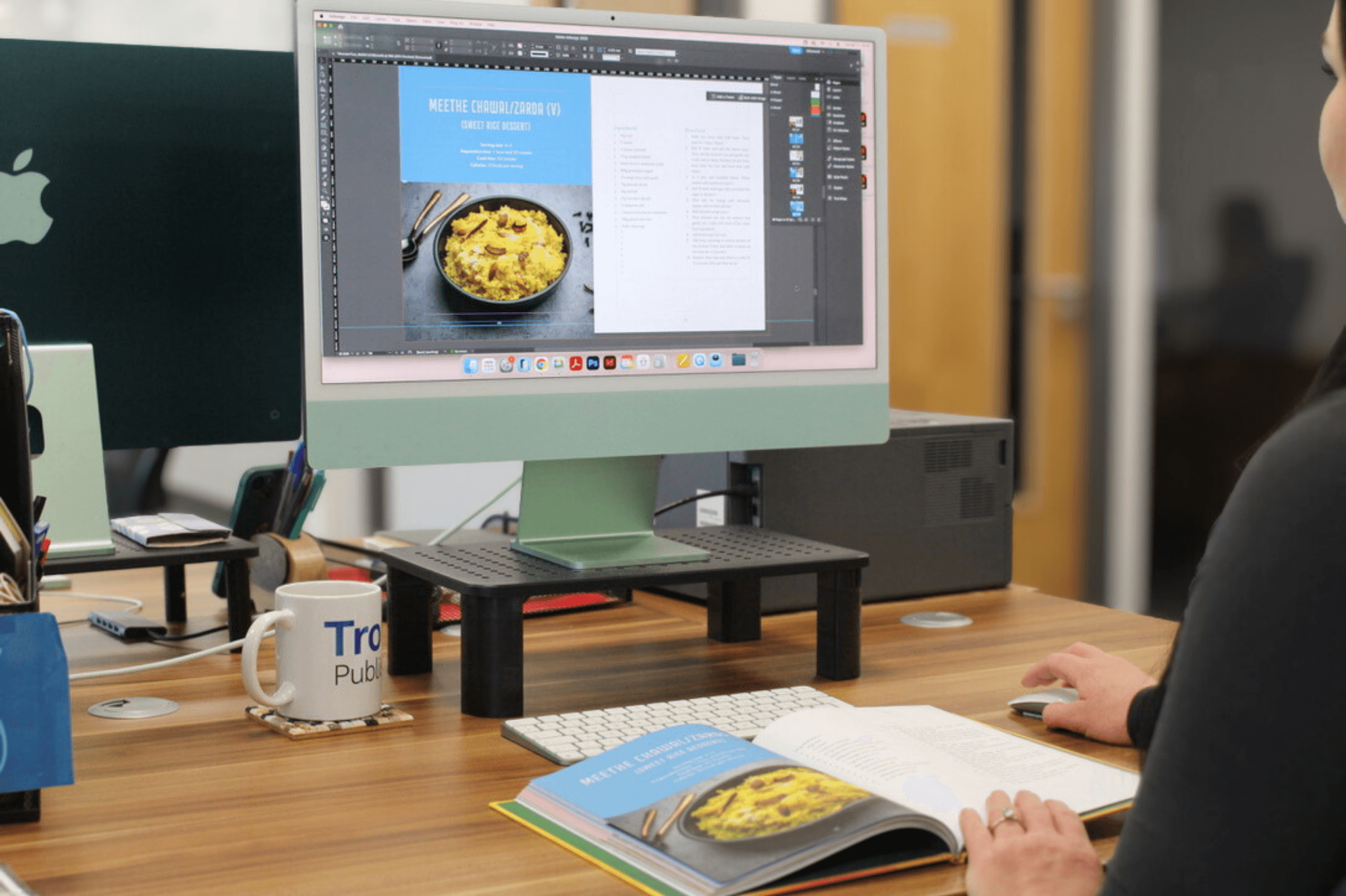 A designer typesetting a cookery book on a large monitor